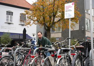 Wethouder Jeroen Bruijns parkeert zijn fiets bij de tijdelijke fiets parkeerplaats aan de Karnemelkstraat