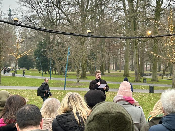 Stadsdichter sttaat op een kistje in het Valkenberppark en leest een gedicht voor